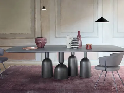 Tavolo Cop con piano in ceramica e base in metallo formata da elementi stilizzati ispirati a bottiglie, calici preziosi e coppe di champagne di Bonaldo